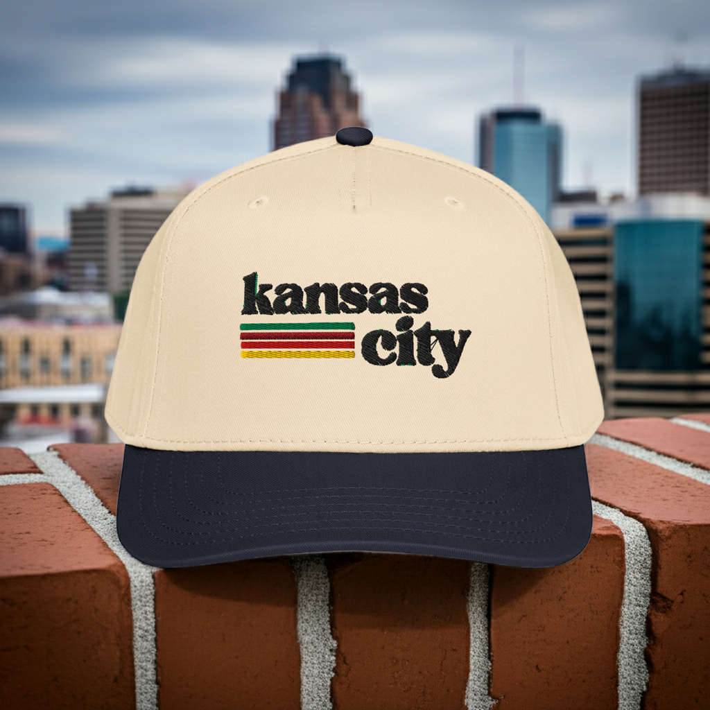 Beige cap with 'Kansas City' text on a brick ledge with city skyline in the background