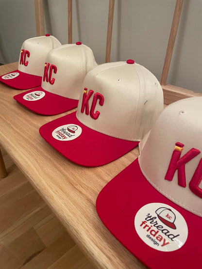 Red and white baseball caps with a logo on a wooden surface